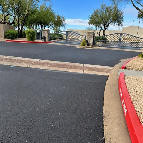 Newly reconstructed asphalt at the Talavera HOA gated entrance with a pavered crosswalk and red fire-lane curbing