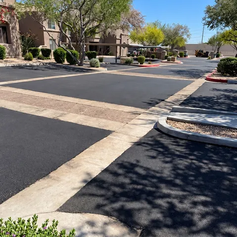 Rebuilt private streets at Talavera HOA with fresh asphalt, pavered crosswalk, and landscaped islands near covered parking